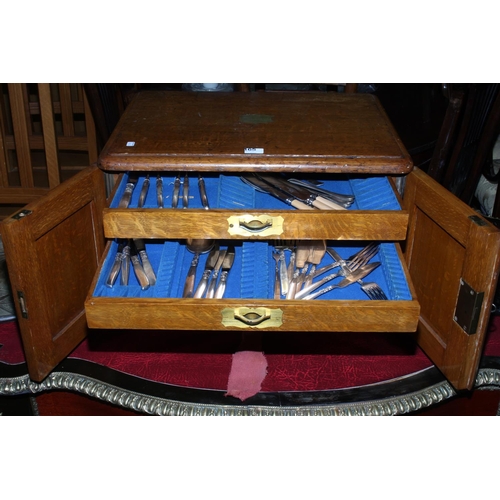 165 - Oak table part canteen of cutlery having double doors concealing four drawers with brass fittings, 5... 