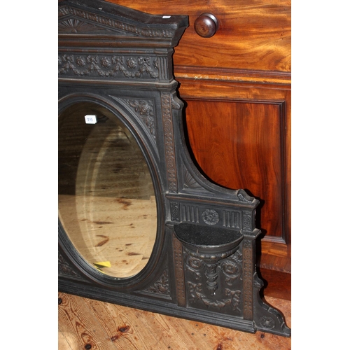 373 - Cast iron arched top framed oval bevelled overmantel mirror, 100cm by 118cm.