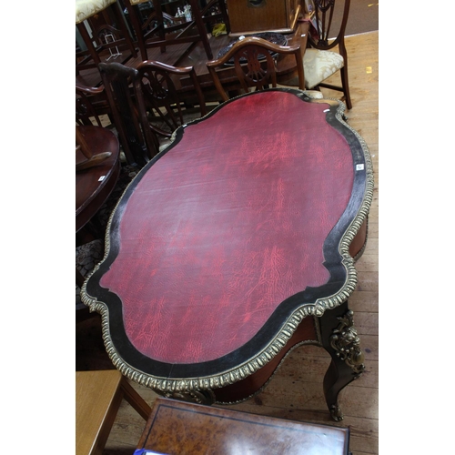 471 - French ebonised and gilt metal mounted bureau plat, of oval shape with inset red leather, frieze dra... 