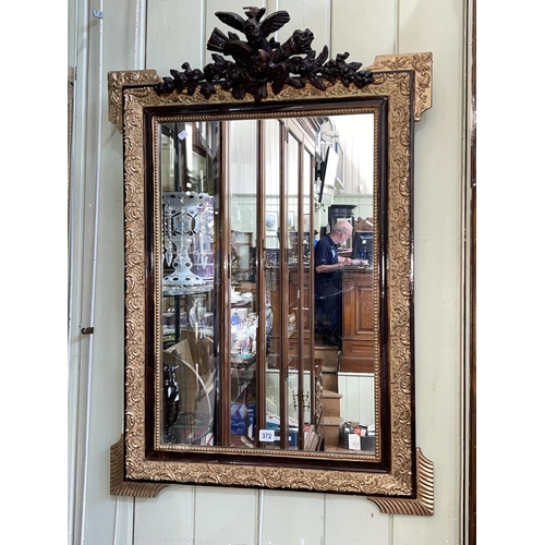 372 - Rectangular gilt framed wall mirror with bird and floral crest, 99cm by 70cm.