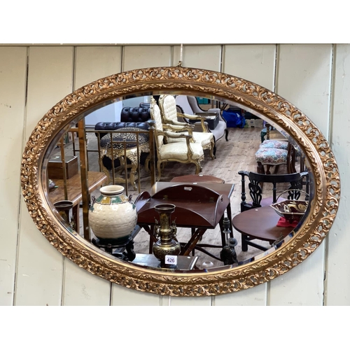 426 - Ornate oval gilt framed bevelled wall mirror, 62cm by 87cm including frame.