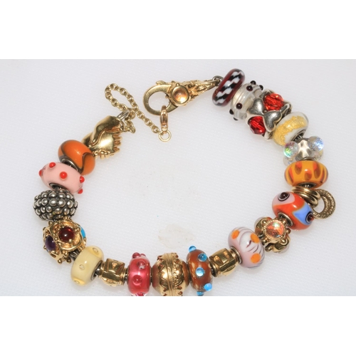 183 - Troll 18 carat gold charm bracelet, having twenty mostly gold and glass charms and with clasped hand... 