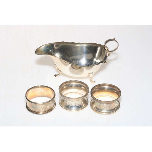 253 - Silver sauce boat, Birmingham 1924, and three silver napkin rings (4).