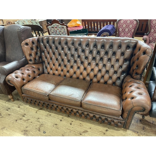 407 - Brown deep buttoned leather three seater wing back Chesterfield settee.