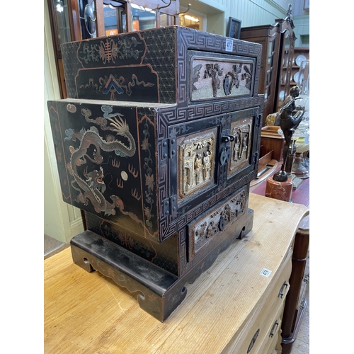 477 - Chinese black lacquered table cabinet having two drawers and two cupboard doors with figure decorati... 