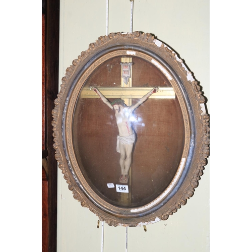 144 - 19th Century crucifix in oval gilt frame behind domed glass, 50cm by 40cm.