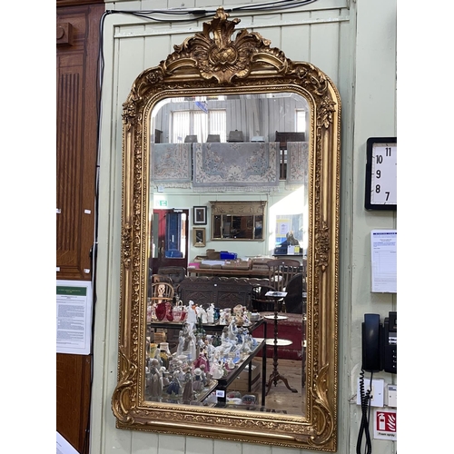 402 - Gilt framed arched top bevelled wall mirror with foliate crest, 155cm by 85.5cm including frame.