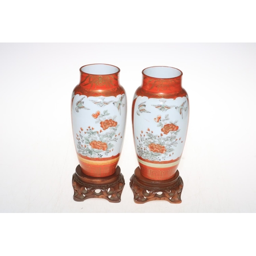 175 - Pair of Oriental vases decorated with figures, birds and fauna on wood stands, 25cm including stands... 