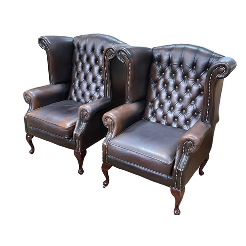 355 - Pair Thomas Lloyd Brown buttoned and studded leather wing back armchairs.