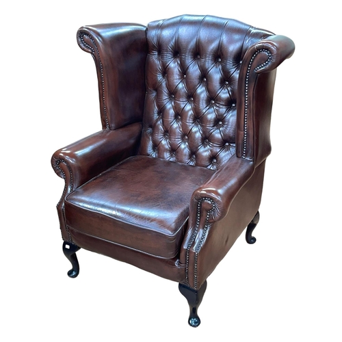 374 - Thomas Lloyd brown deep buttoned back and studded leather wing armchair.