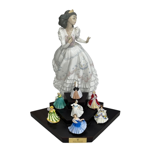 11 - Large Lladro Quinceanera figure and seven Royal Doulton miniature figures and stand.