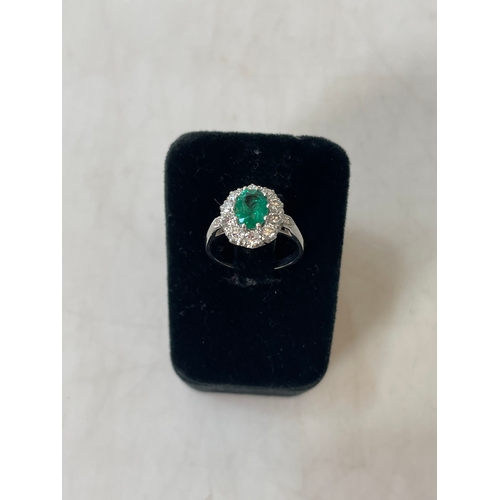 192 - Emerald and diamond platinum ring, having oval emerald bordered with ten diamonds and diamond set sh... 