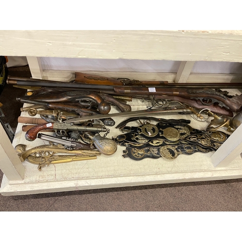 121 - Full shelf of brass and metalwares, mantel clock, model guns, martingales, pewter tankards, etc.