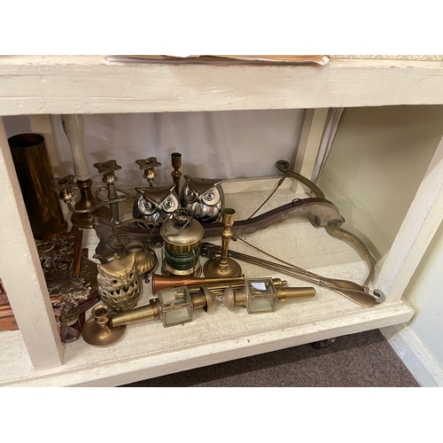 121 - Full shelf of brass and metalwares, mantel clock, model guns, martingales, pewter tankards, etc.