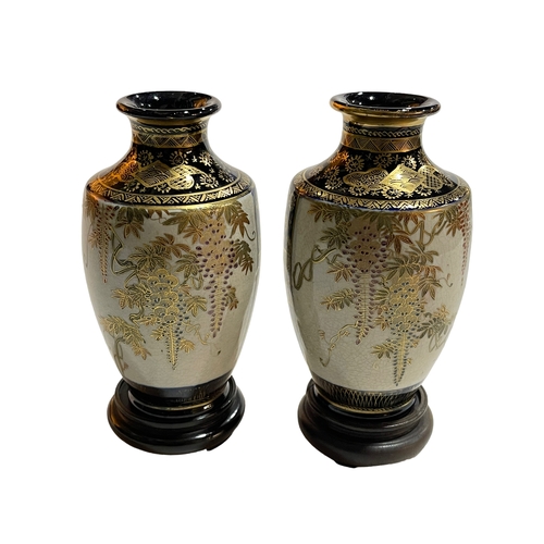 151 - Pair of Satsuma vases decorated with flora and fauna on wood stands, 17cm.