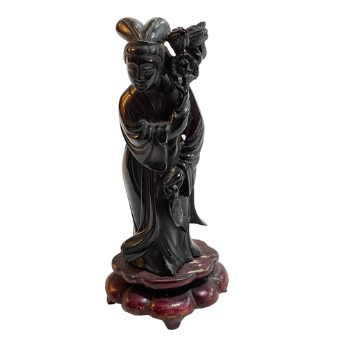 174 - Chinese carved cherry amber figure on wood base, 20cm high.