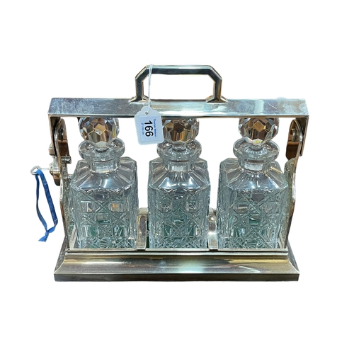 166 - Three bottle tantalus in silver plated stand, 30cm high.