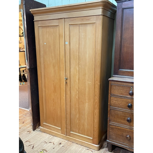 374 - Pine wardrobe having two panelled doors enclosing base drawer, 201.5cm by 120.5cm by 57cm.