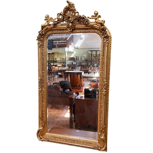 363 - Gilt framed bevelled overmantel mirror having foliate crest supported by putti, 158cm by 84cm.