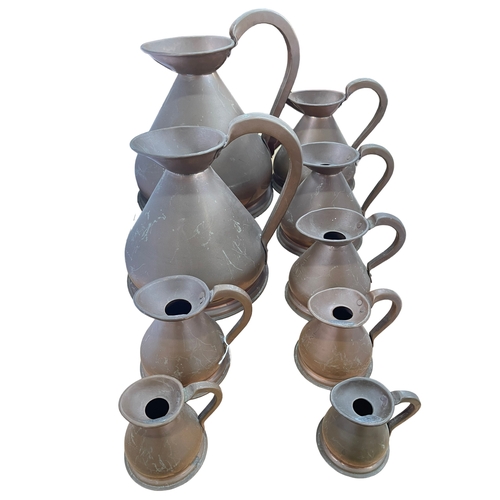 42 - Nine replica copper measure jugs.