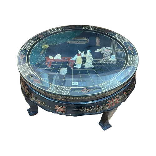 423 - Oriental black lacquered circular coffee table with applied figure decoration, 39cm by 76cm diameter... 