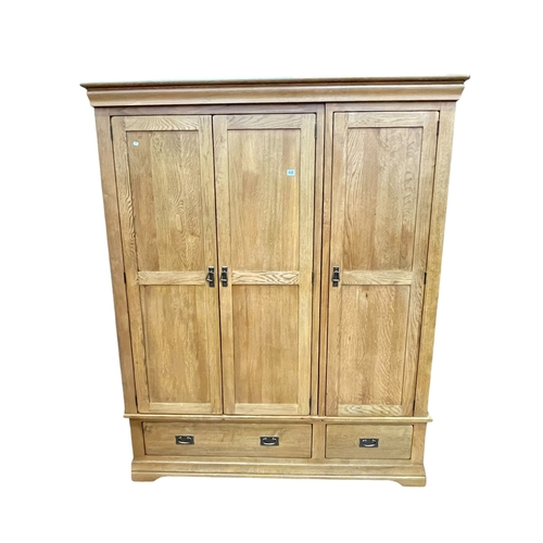 432 - Contemporary oak wardrobe having three doors above two base drawers, 193cm by 156.5cm by 63cm.