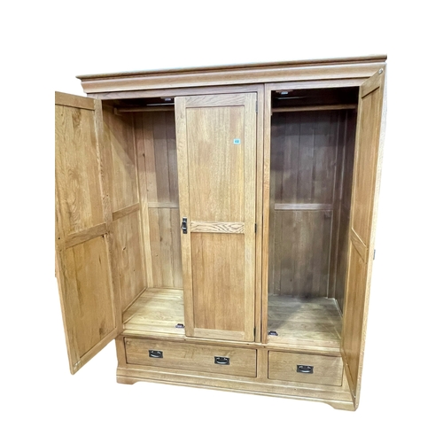 432 - Contemporary oak wardrobe having three doors above two base drawers, 193cm by 156.5cm by 63cm.