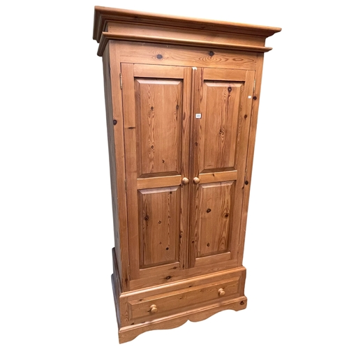 436 - Pine wardrobe having two doors above a base drawer, 201cm by 103cm by 62cm.