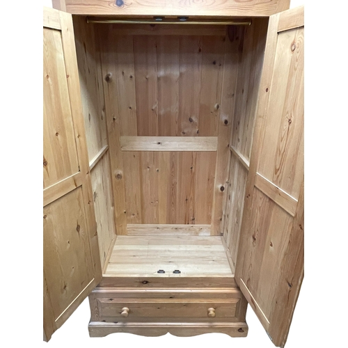 436 - Pine wardrobe having two doors above a base drawer, 201cm by 103cm by 62cm.