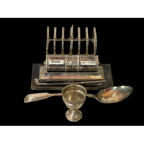 247 - Silver golf theme desk perpetual calendar, silver seven bar toast rack, silver egg cup and George IV... 