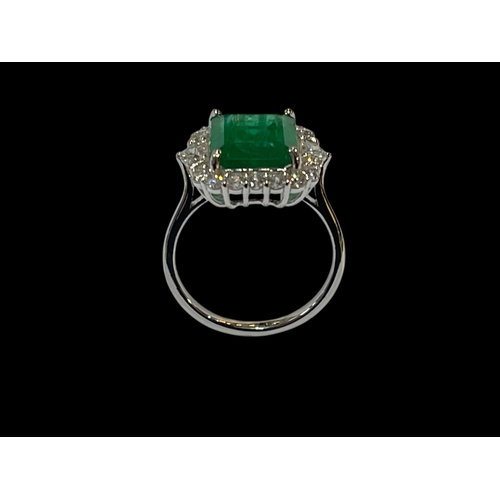 128 - Emerald and diamond cluster ring set in 18 carat white gold, rectangular emerald 12mm by 9mm, 4.65 c... 