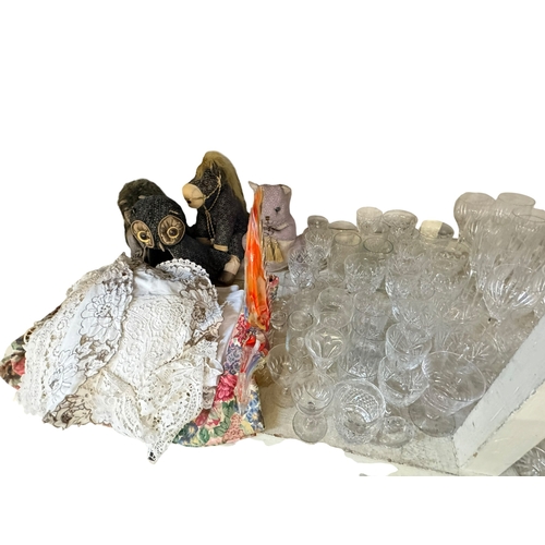 94 - Large collection of glassware, linen and soft toys.