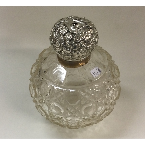 148 - CHESTER: A heavy silver mounted glass scent bottle of chased form. Est. £25 - £30.