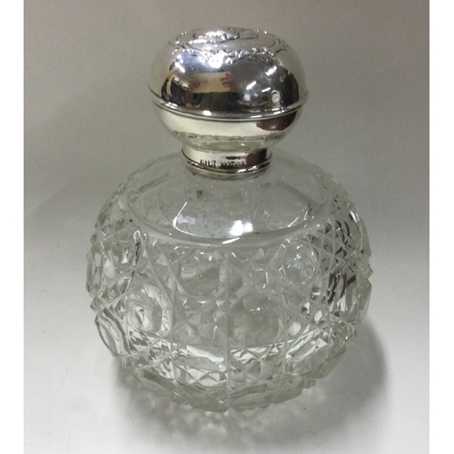 134 - A large silver mounted glass scent bottle with cherub decoration. Birmingham 1906. Est. £120 - £150.