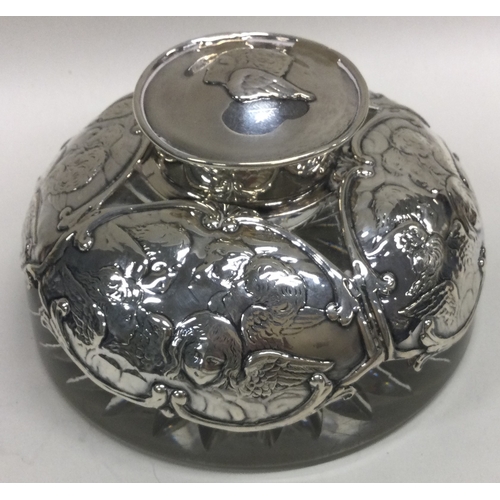 375 - A silver and glass inkwell embossed with cherubs. Birmingham 1904. By William Comyns. Est. £100 - £2... 