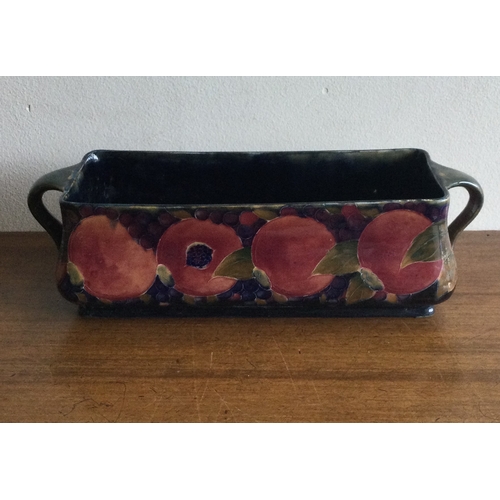 247 - WILLIAM MOOCROFT: A rectangular twin handled trough on green background of pomegranate design. 1913 ... 