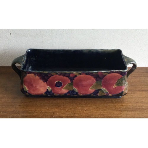 247 - WILLIAM MOOCROFT: A rectangular twin handled trough on green background of pomegranate design. 1913 ... 