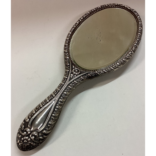 303 - CHESTER: A chased silver mirror embossed with flowers. Est. £80 - £120.