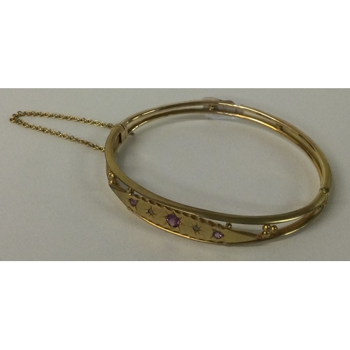 547 - A 9 carat amethyst and diamond hinged bangle with safety chain. Approx. 7 grams. Est. £150 - £200.