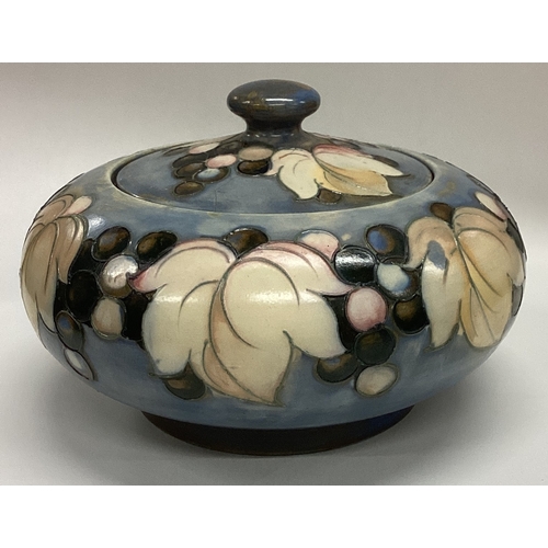 777 - WILLIAM MOORCROFT: A squat powder jar and cover decorated with leaves and berries. Est. £100 - £150.