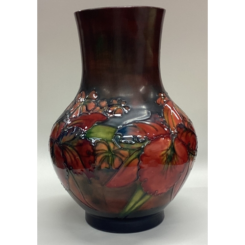 779 - WILLIAM MOORCROFT: A large red ground vase decorated with flowers and leaves. Est. £100 - £150.