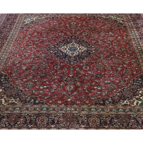 916 - A good large red ground carpet with tassel decoration. Approx. 190 cms x 380 cms. Est. £200 - £300.