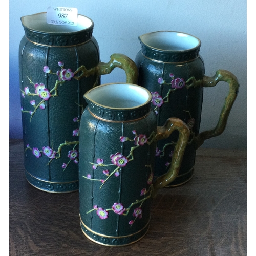 987 - A set of three stoneware jugs with aesthetic decoration. Est. £30 - £50.