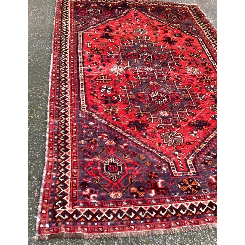 1673 - A small Oriental rug in red ground. Approx. 150 cms x 220 cms. Est. £50 - £80.