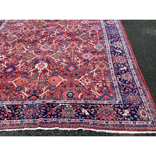 1674 - A large red ground carpet decorated in bright colours. Approx. 275 cms x 340 cms. Est. £100 - £150.