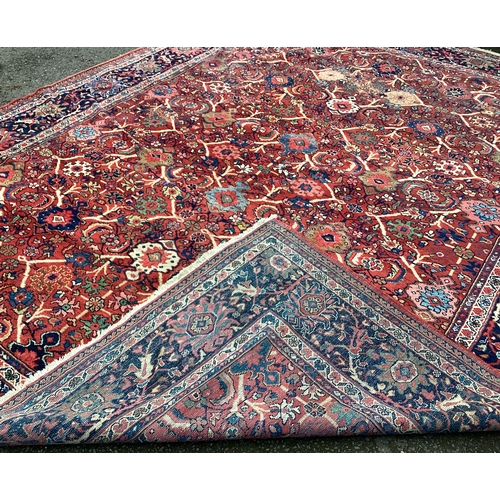 1674 - A large red ground carpet decorated in bright colours. Approx. 275 cms x 340 cms. Est. £100 - £150.