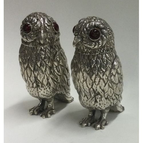 103 - A pair of silver peppers in the form of owls with red eyes. Approx. 125 grams. Est. £200 - £300.