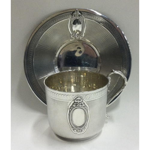 129 - A French silver cup and saucer with engine turned decoration. Retailed by Hamilton & Co. Approx. 181... 