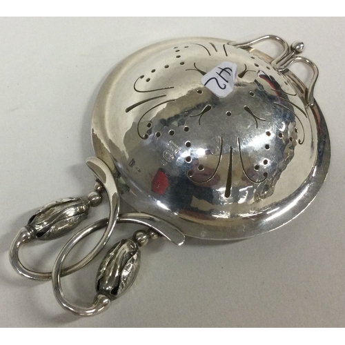 412 - GEORG JENSEN: A silver tea strainer with blossom decoration. Approx. 53 grams. Est. £250 - £300.