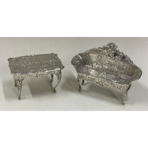 101 - CHESTER: A miniature silver sofa and table. 1900. Approx. 38 grams. Est. £40 - £60.